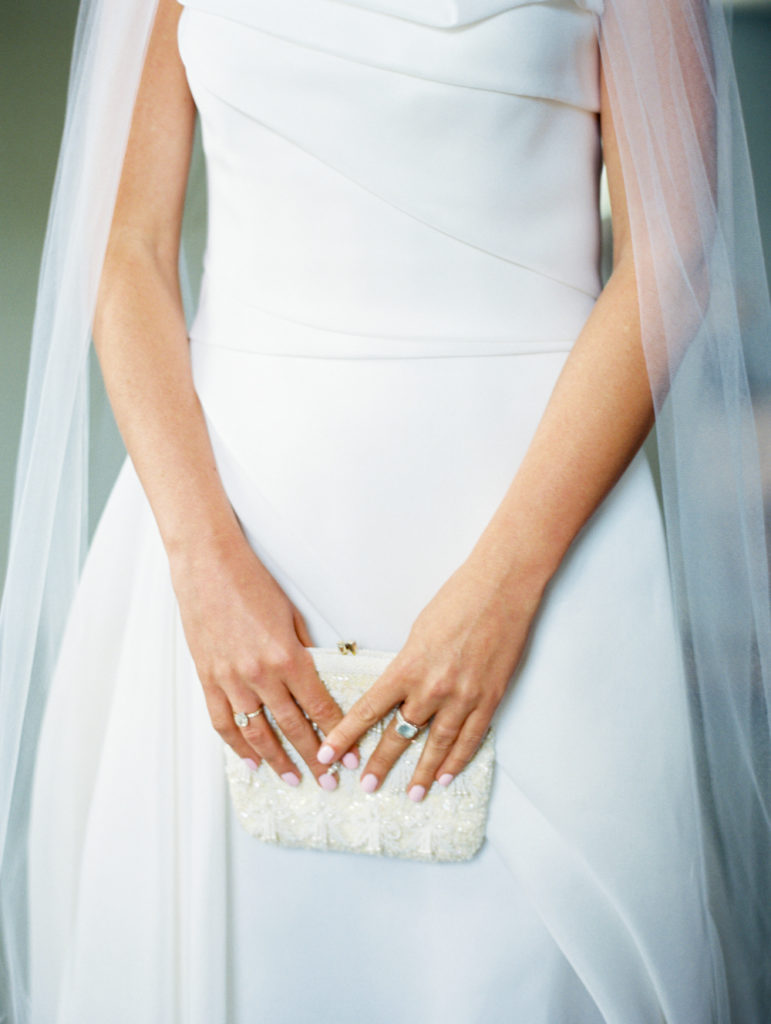 bride holding vintage purse and wearing blue ring