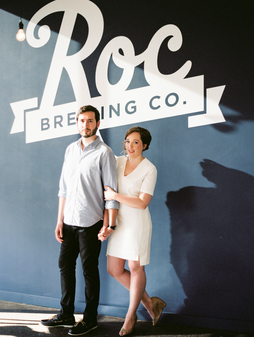 Roc Brewing Co Engagement Photo Couple standing by sign Rochester NY Mary Dougherty