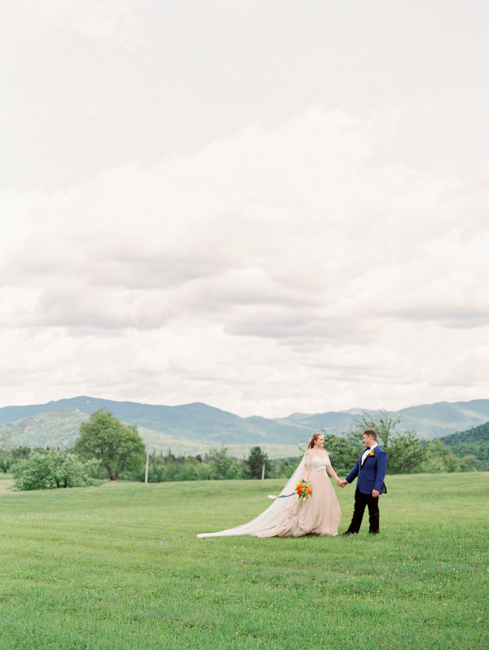 bride and groom walking with a mountain view on their lake placid wedding day | Mary Dougherty