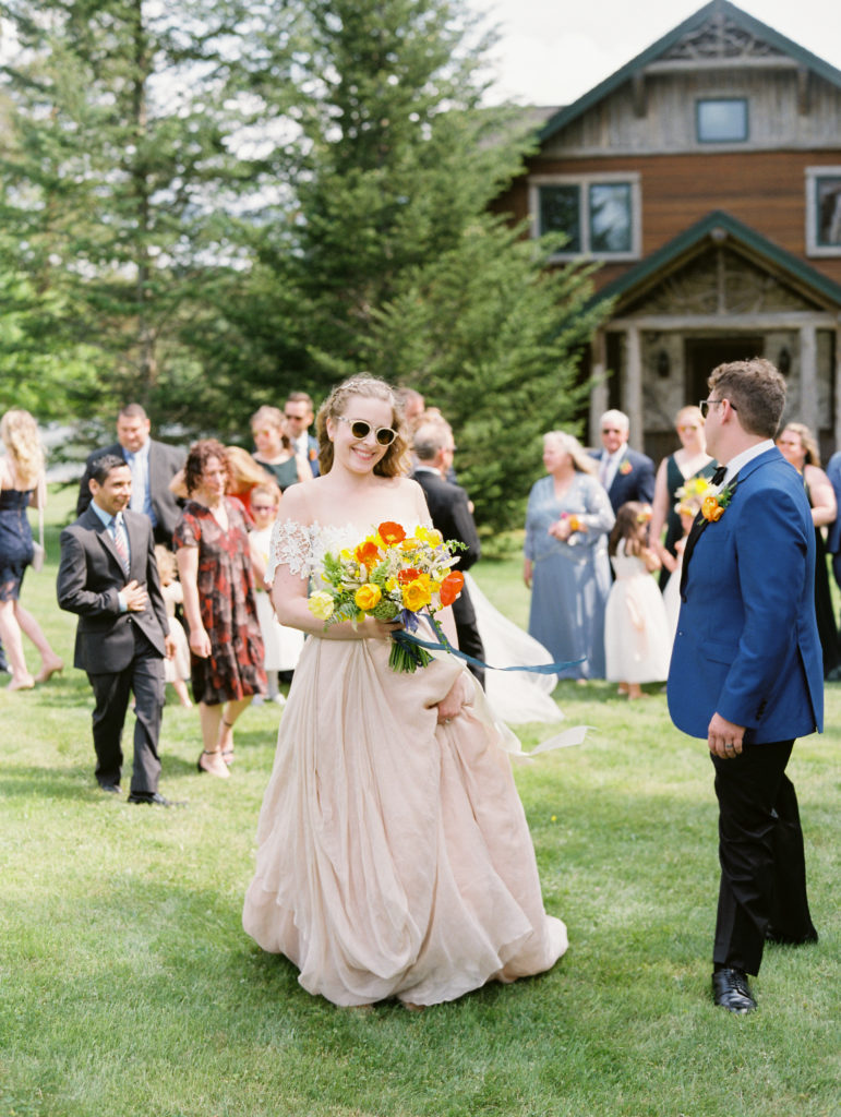 bride smiling holding her bouquet wearing sunglasses in Lake Placid | Mary Dougherty
