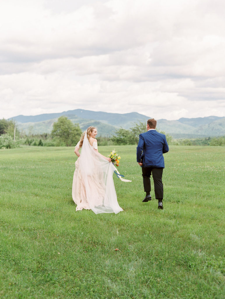 Wedding couple running toward mountains