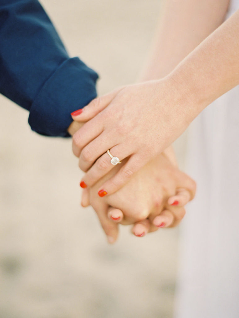 engagement ring and red nail polish while holding hands
