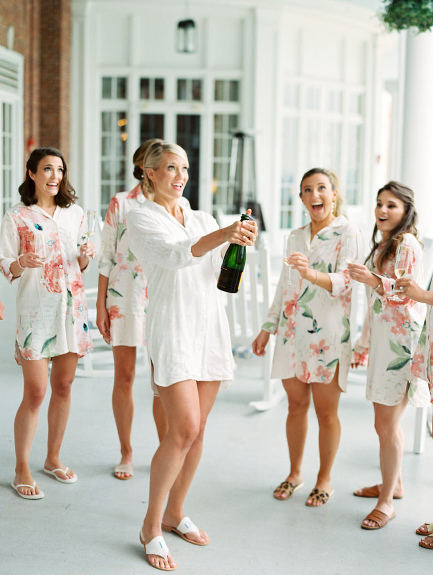 Bride popping Champagne open on porch of Otesaga | Mary Dougherty