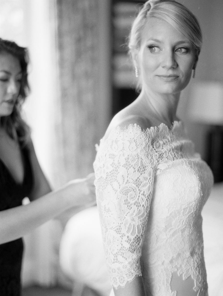 bride looking over shoulder getting lace topper buttoned up
