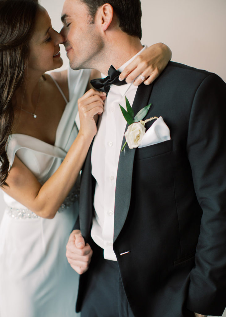 bride about to kiss groom while straightening bowtie | Mary Dougherty