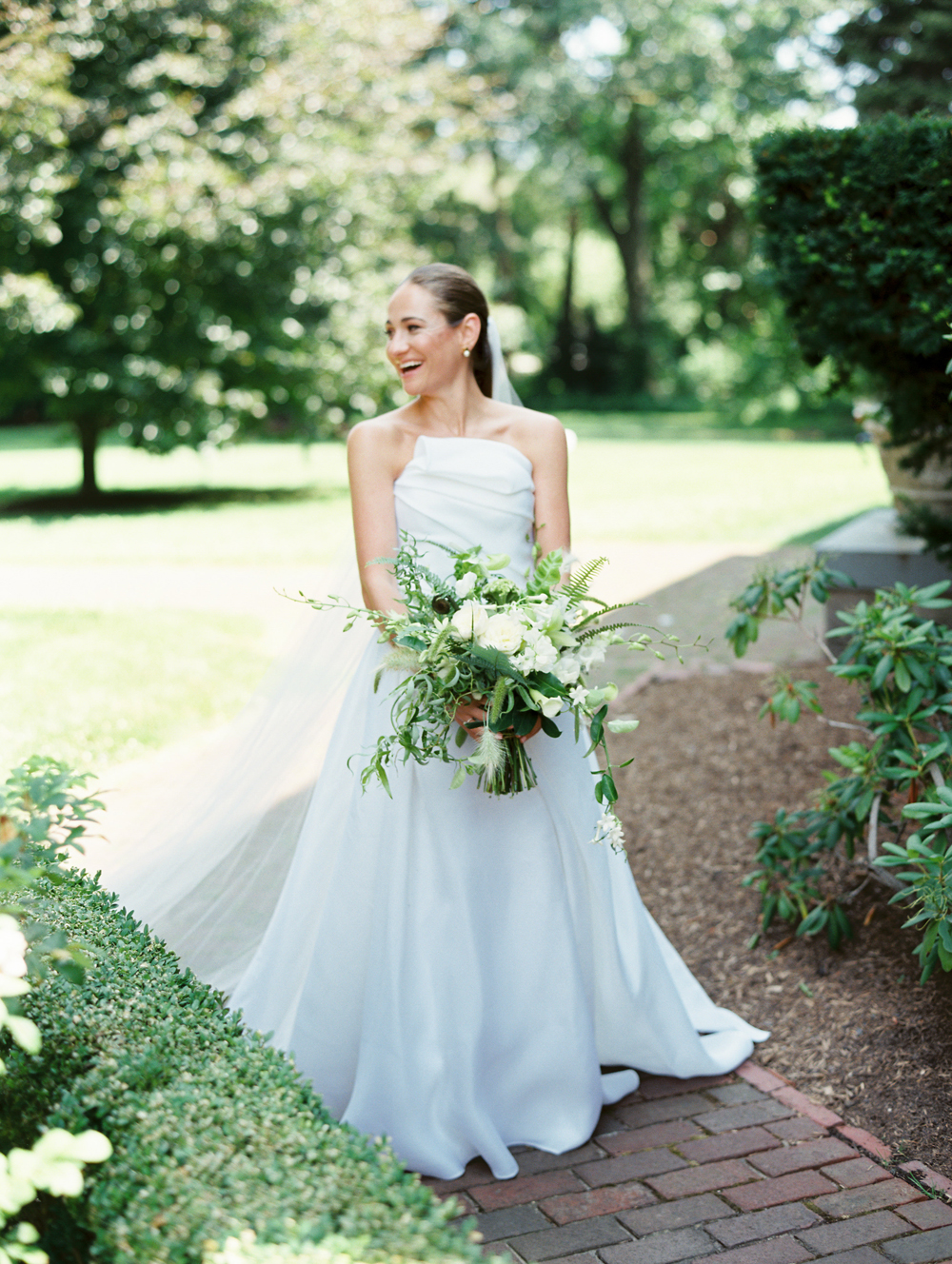 Bride stands outside holding bouquet and laughs at Genesee Valley Club wedding by Mary Dougherty