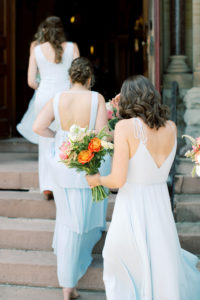 bridesmaids in blue dresses walking up steps to church for ceremony