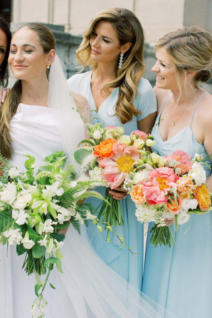 bride and bridesmaids close up of flowers with blue dresses and bright pink bouquets by Arena's | Mar Dougherty