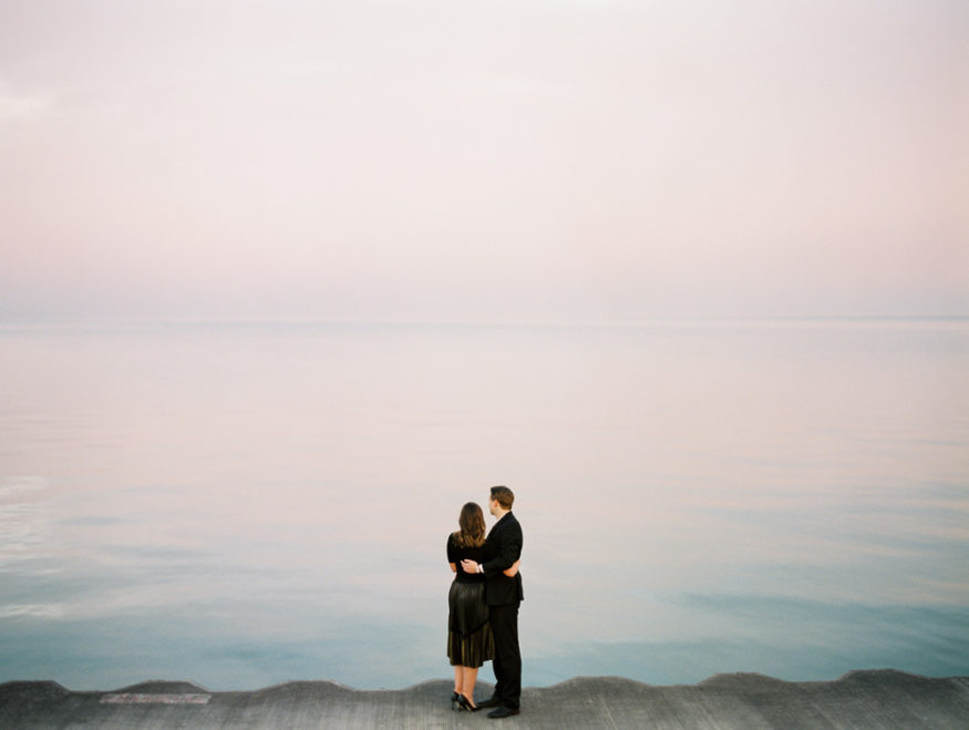 couple looks out to waterfront during sunset in Chicago Engagement Session by film wedding photographer Mary Dougherty