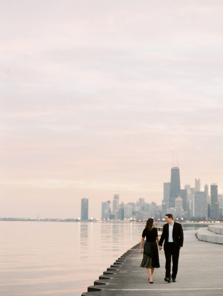 couple walks during sunset on the waterfront with Chicago city skyline in the background by film wedding photographer Mary Dougherty