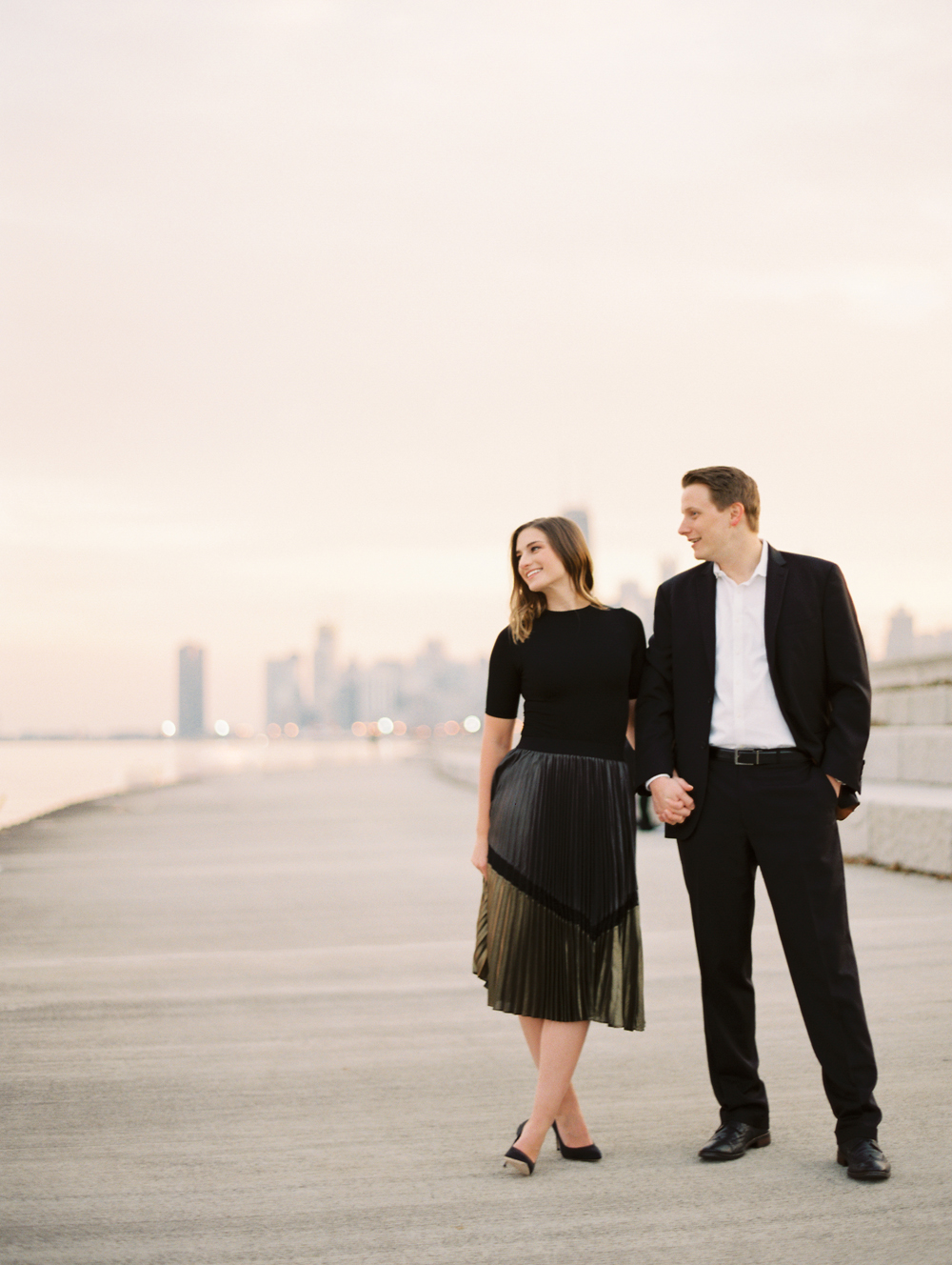 couple smiles looking towards water on the riverfront in Chicago engagement photo by film wedding photographer Mary Dougherty
