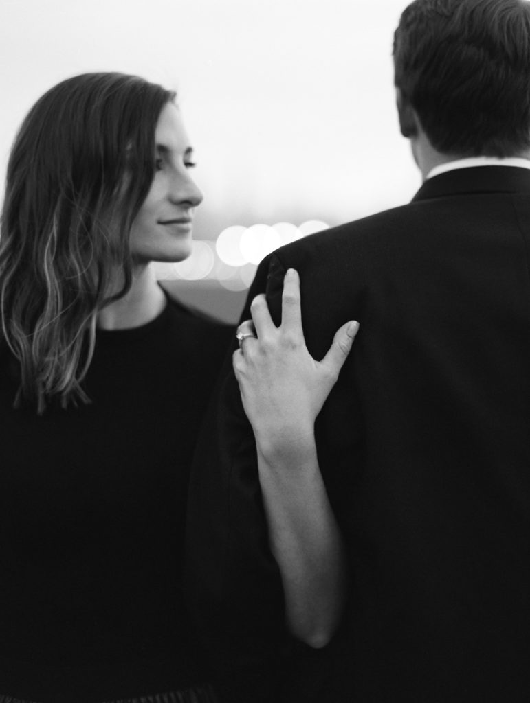 portrait of woman holding man with ring looking over shoulder bw abstract modern engagement photo on film by Mary Dougherty