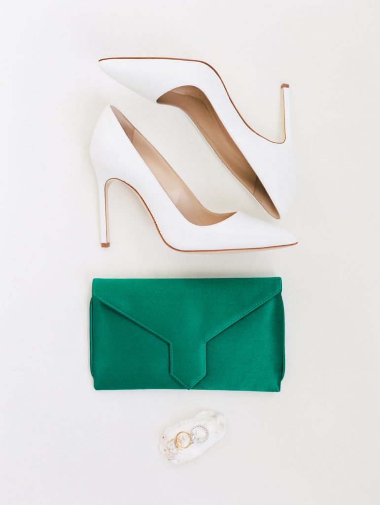 white Jimmy Choo heels, emerald green purse and wedding rings flatlay for modern holiday wedding detail inspiration Mary Dougherty Photography