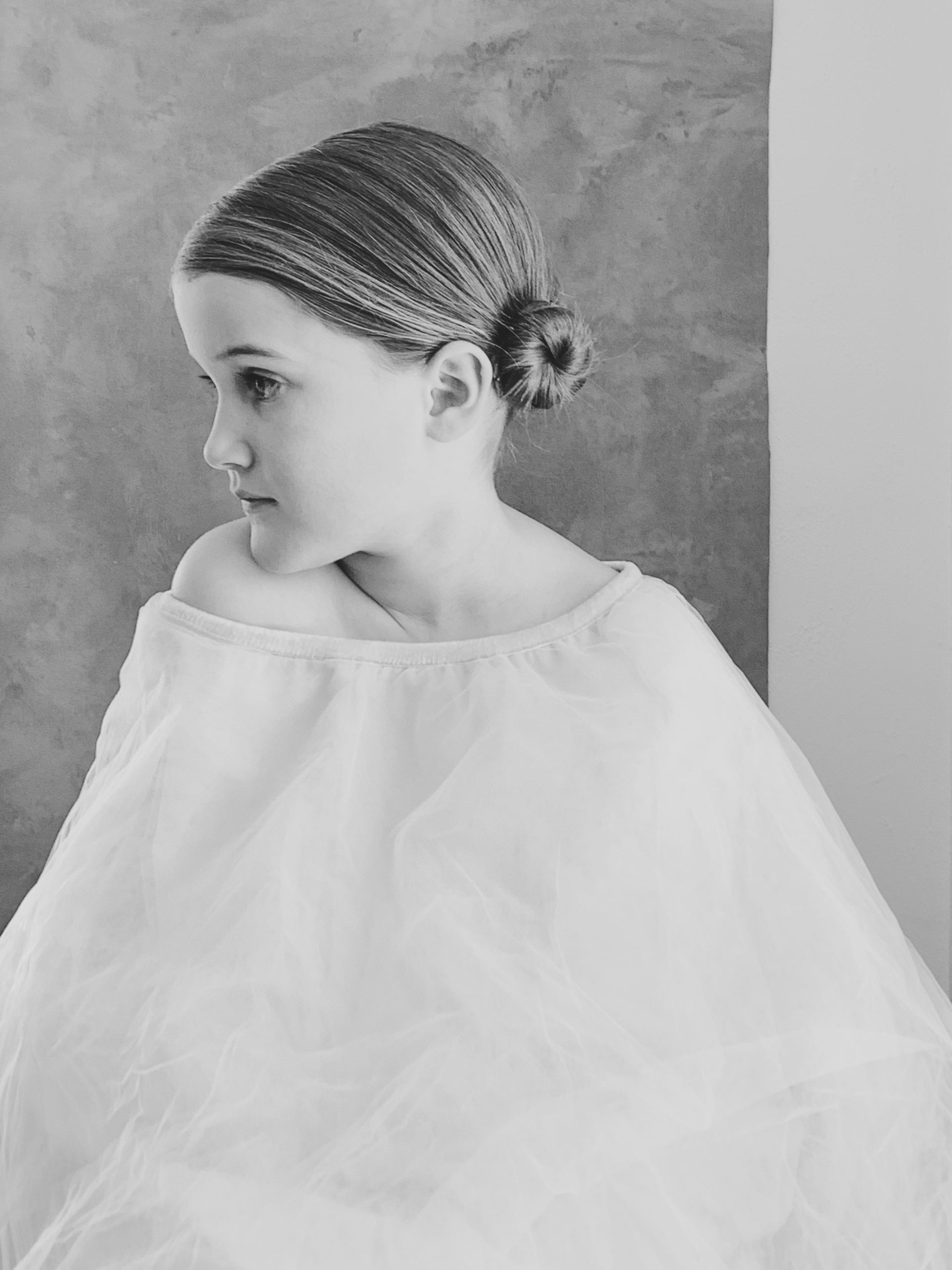 little girl poses for portrait with bun in hair and couture like dress old hollywood black and white photo | iphone photography by Mary Dougherty