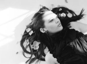 black and white photo of model laying down with flowers in hair and light across face dress by Leanne Marshall Mary Dougherty Photography