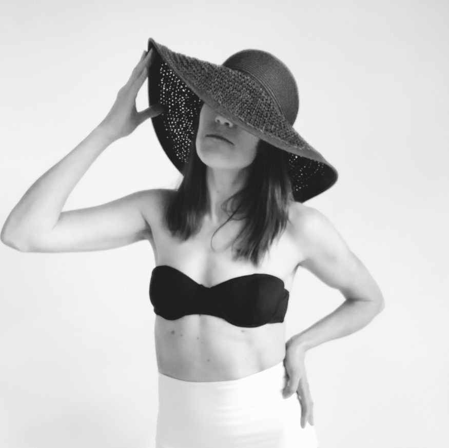 bw image self portrait of woman with hands on black straw hat in bathing suit 