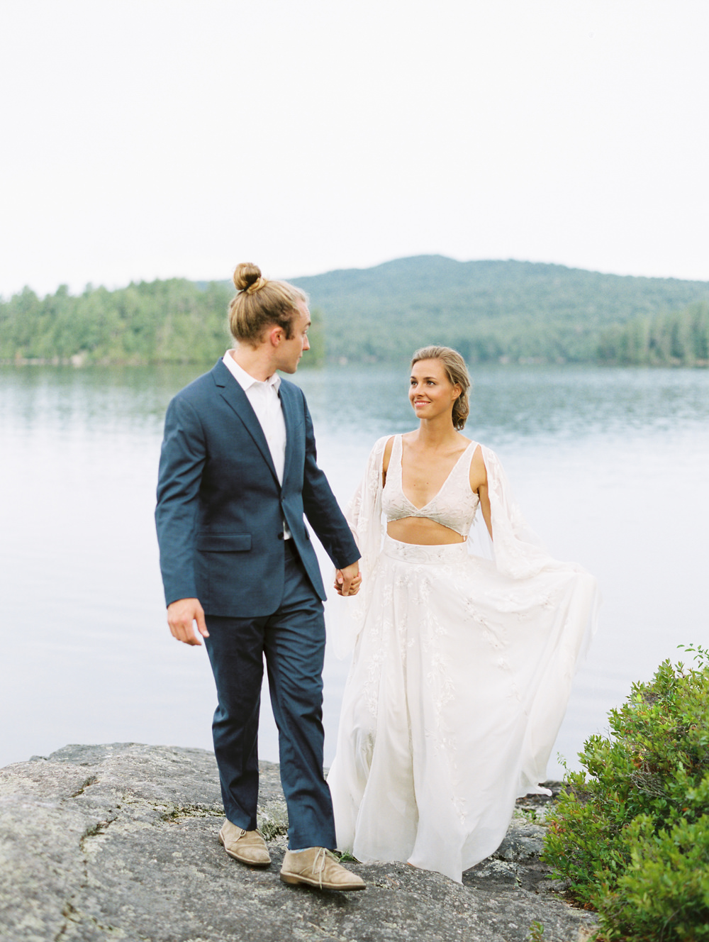 bride smiles at groom while walking on rocks Adirondack Island Elopement by Mary Dougherty