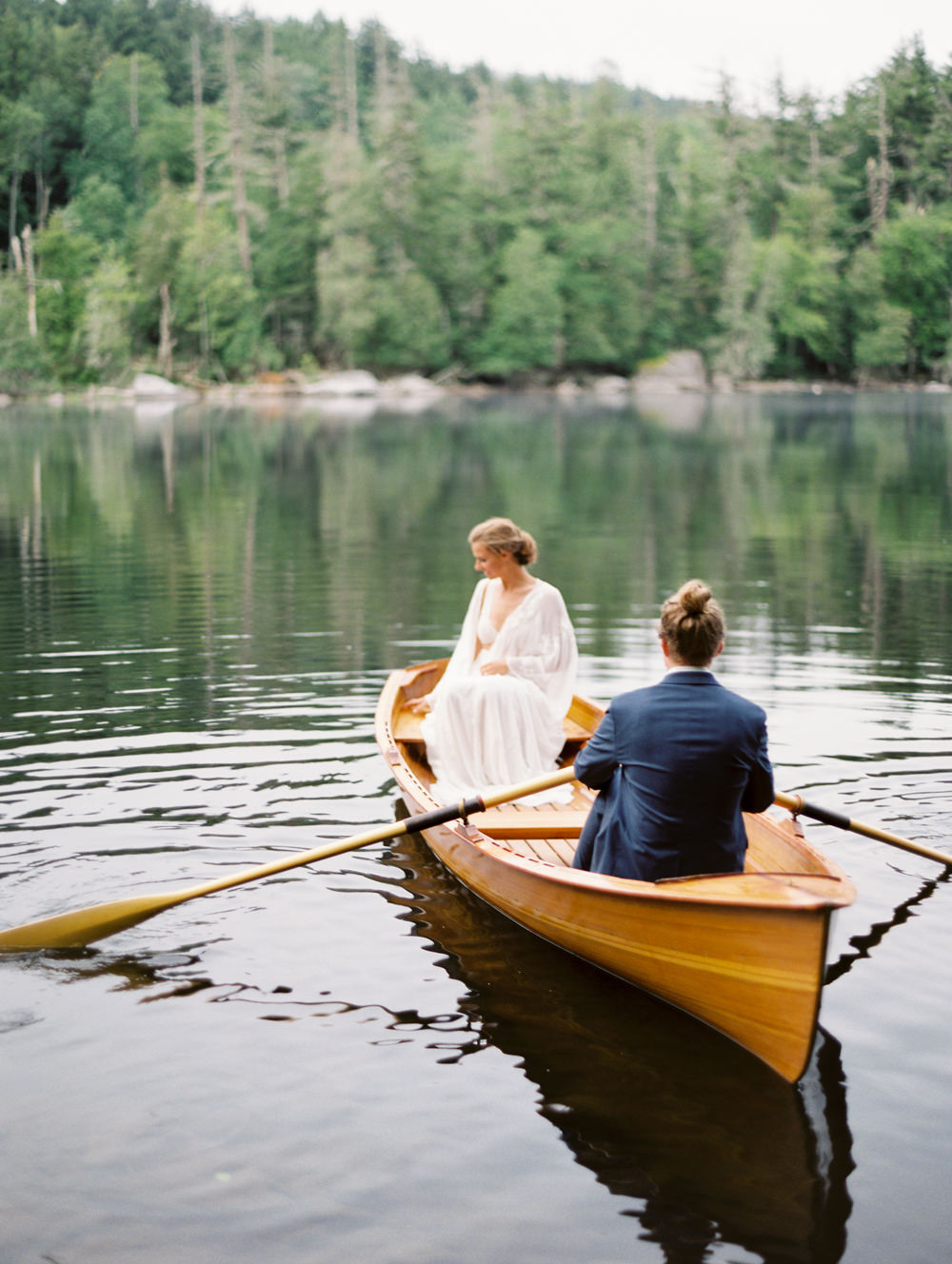 couples paddles out in water in wooden row boat guide boat in Adirondacks for island elopement | film photography workshop | Mary Dougherty