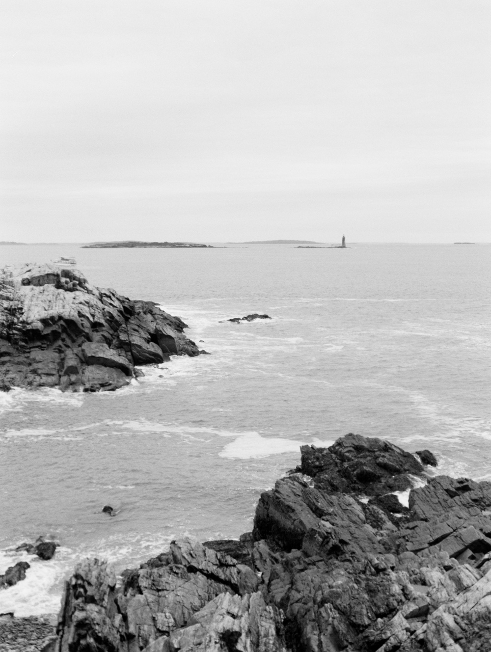 view of ocean and islands from Portland Head Light Lighthouse and park in black and white by Mary Dougherty