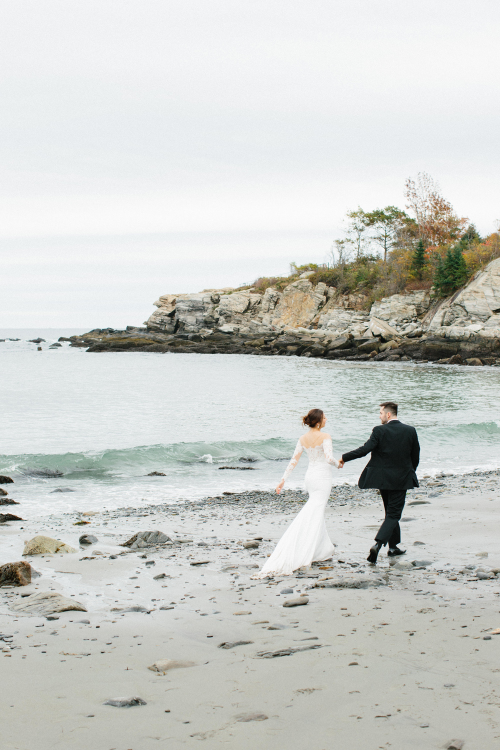 bride and groom run on beach at Portland Head Light Beach during their Maine fall elopement | Mary Dougherty 