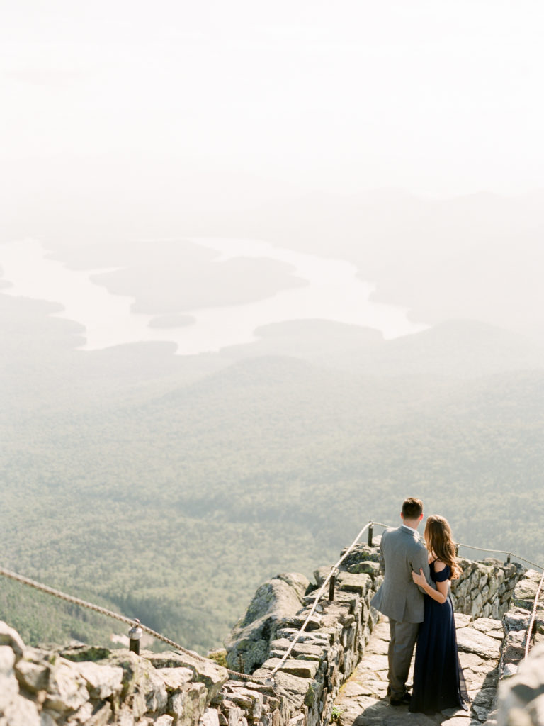 couple looks out to lake from mountain view of whiteface mountain in lake placid by Mary Dougherty