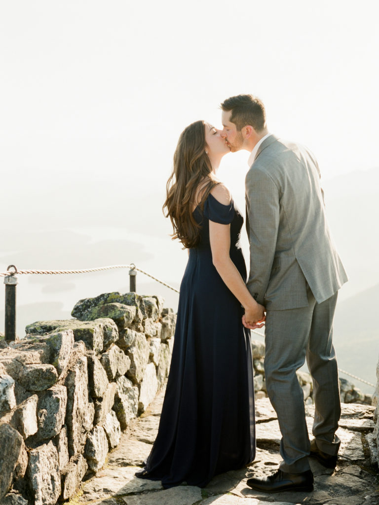 man and woman kiss dressed up on rocky steps of whiteface mountain during engagement session