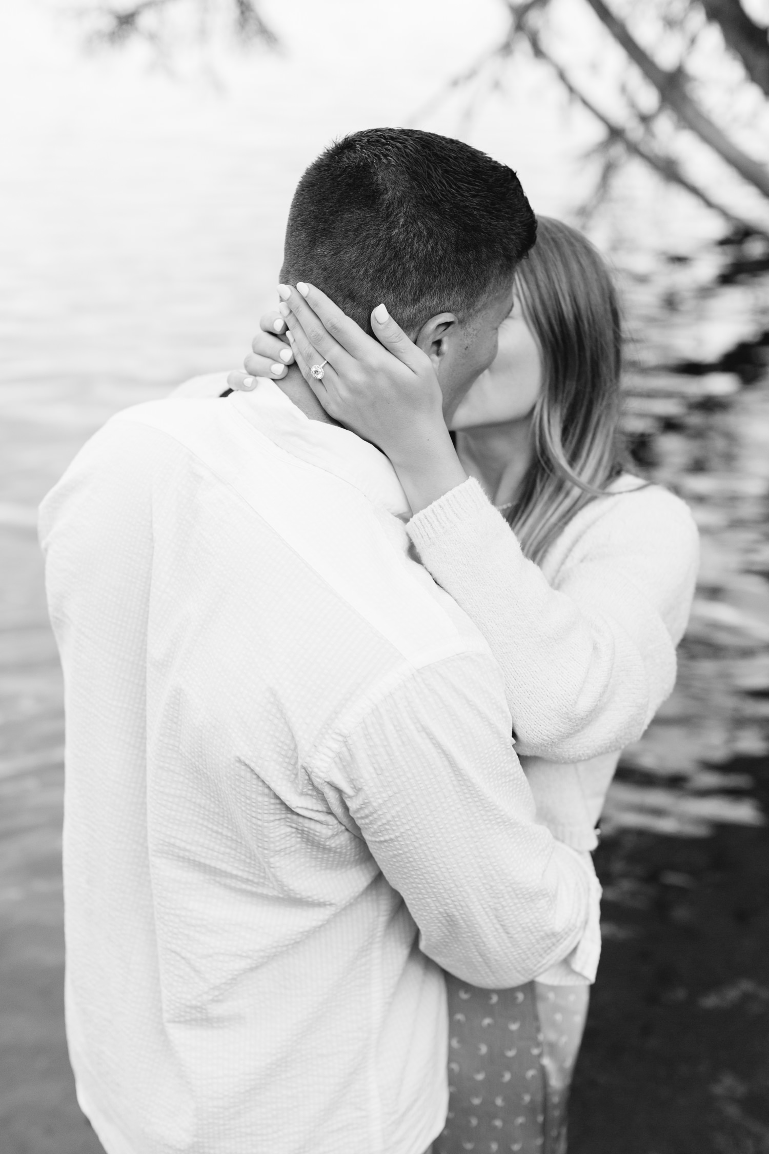 black and white photo of couple kissing with faces hidden ring on hand