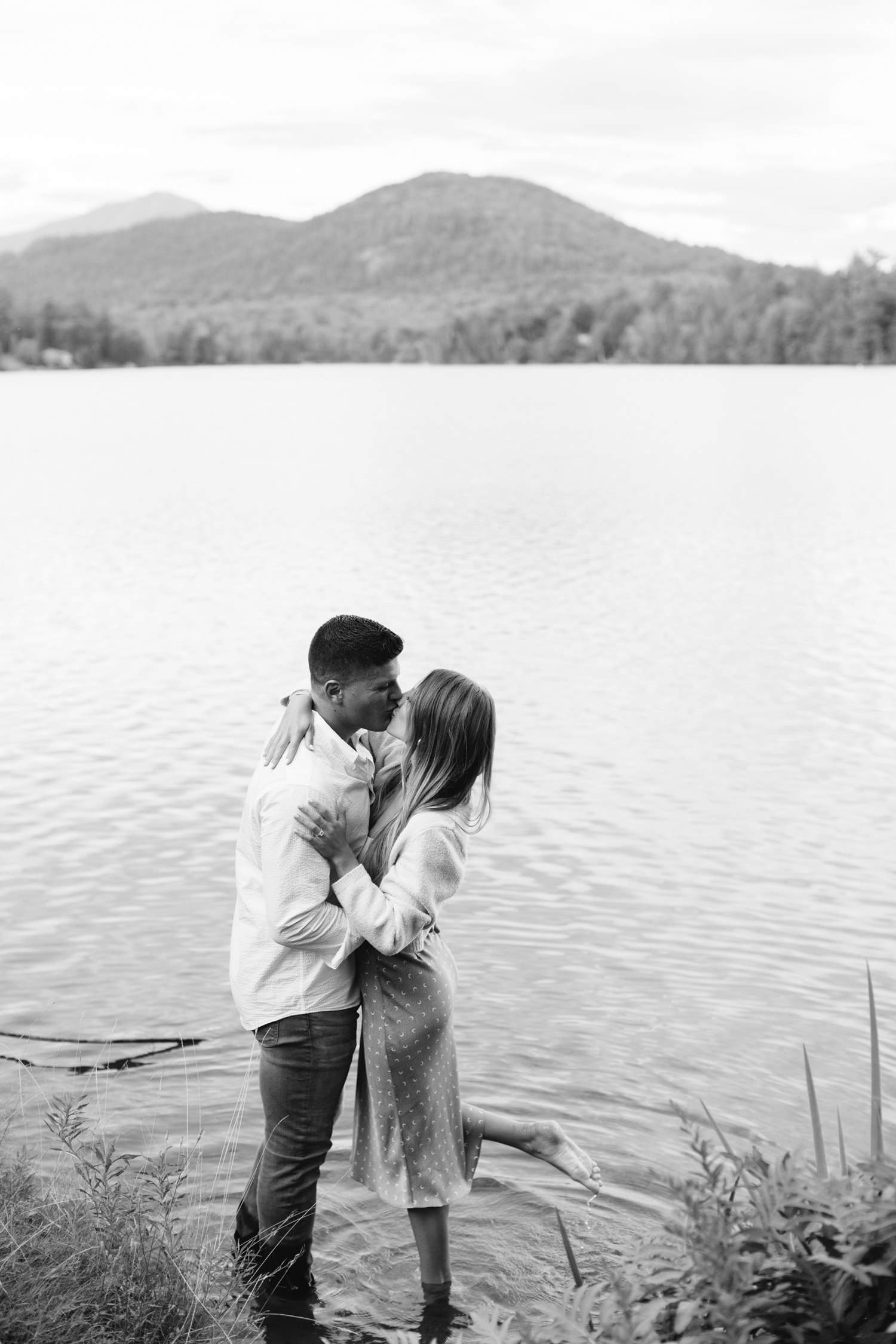 couple stands in Mirror Lake kissing after just getting engaged