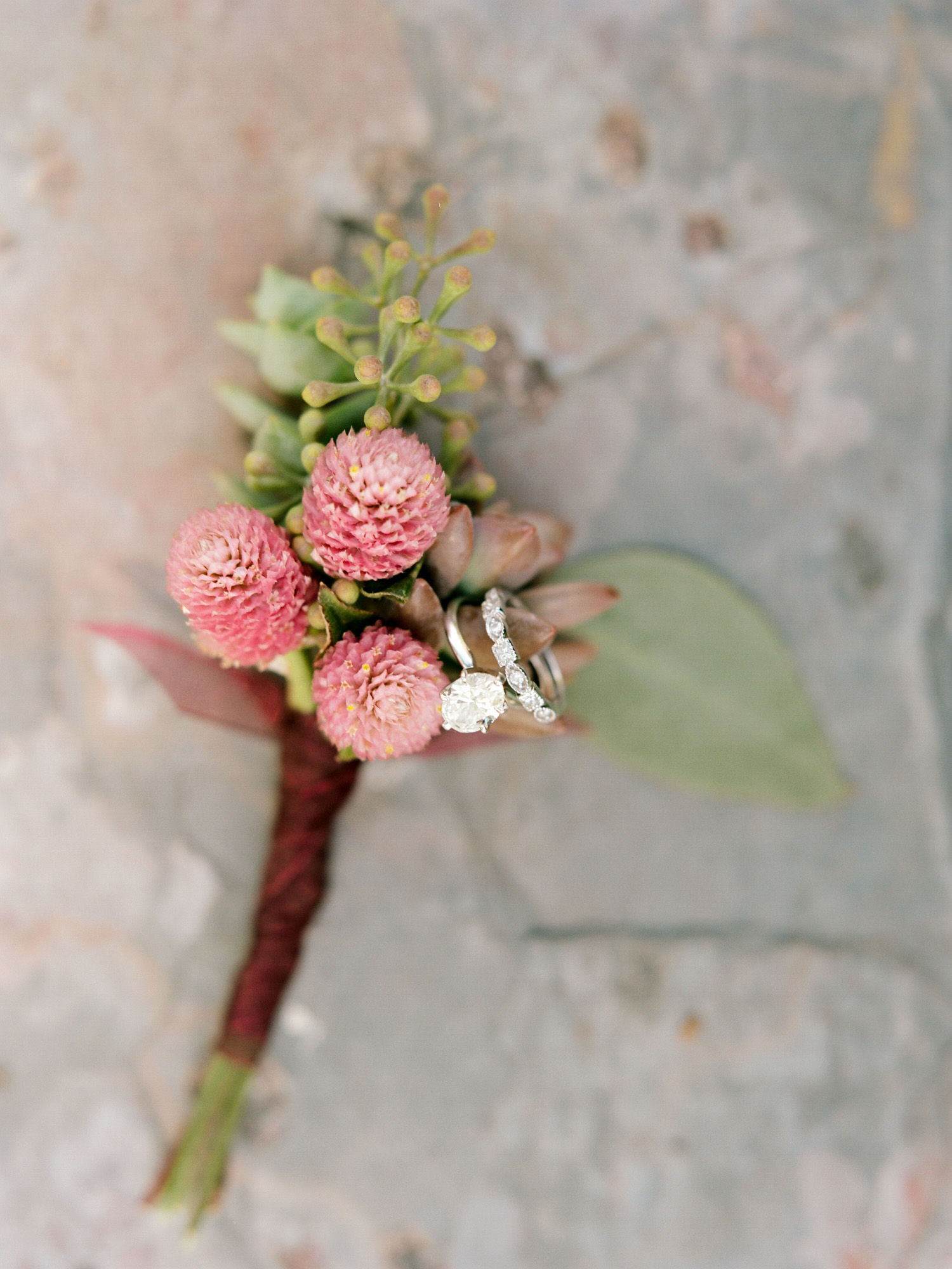 Maroon and green boutonnière with wedding bands from a backyard wedding photographed by Mary Dougherty