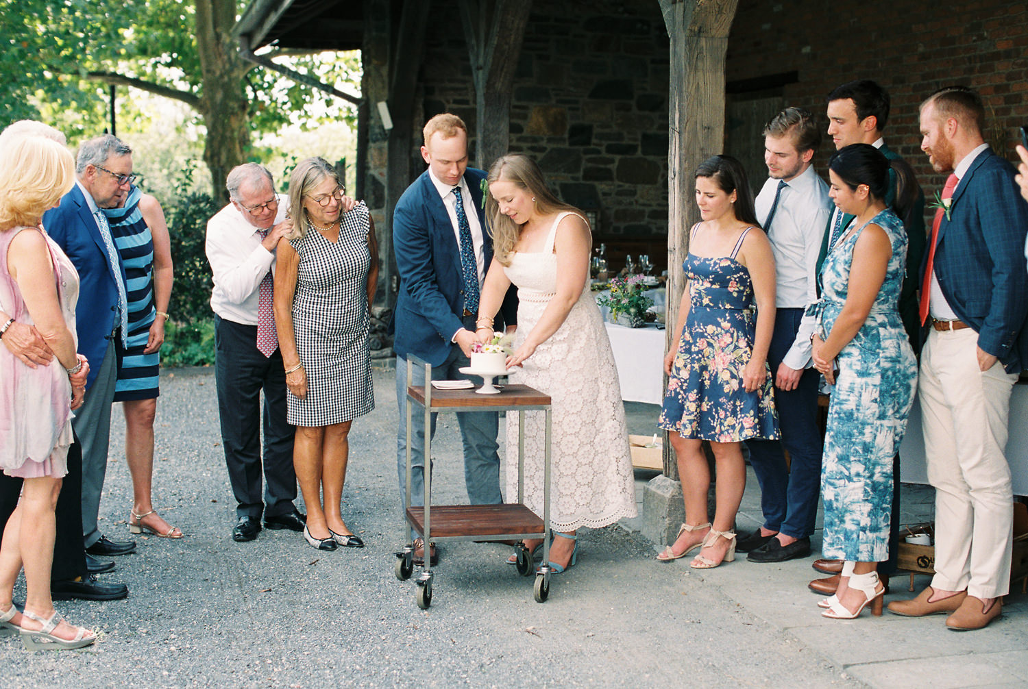 Family looks on as bride and groom cut wedding cake during an intimate picnic wedding | photographed by Mary Dougherty 