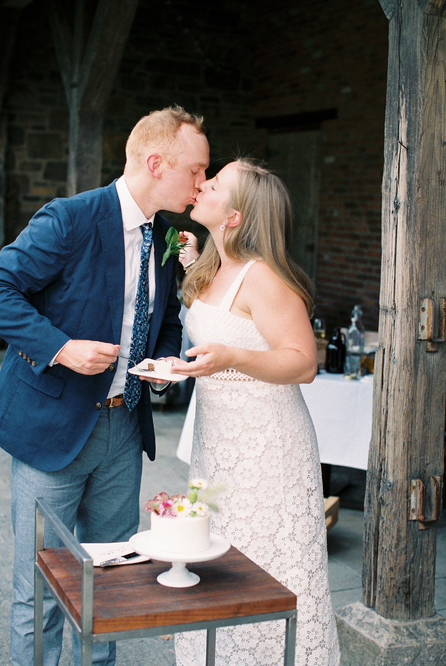bride and groom kiss after cutting wedding cake at a Blue Hill farm NY wedding | photographed by Mary Dougherty 