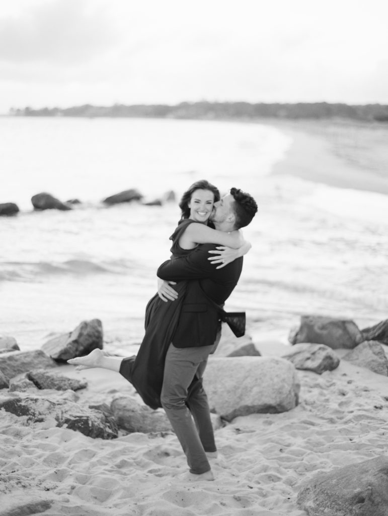 Couple in black and white embracing on the sand in their beach engagement photo session | Mary Dougherty destination film wedding photographer