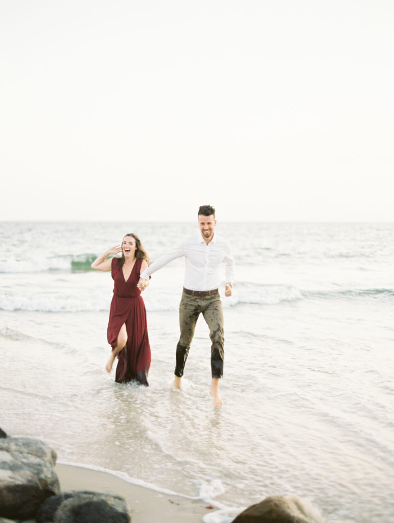 Couple running through the water in a casual beach engagement photo | Mary Dougherty destination film wedding photographer
