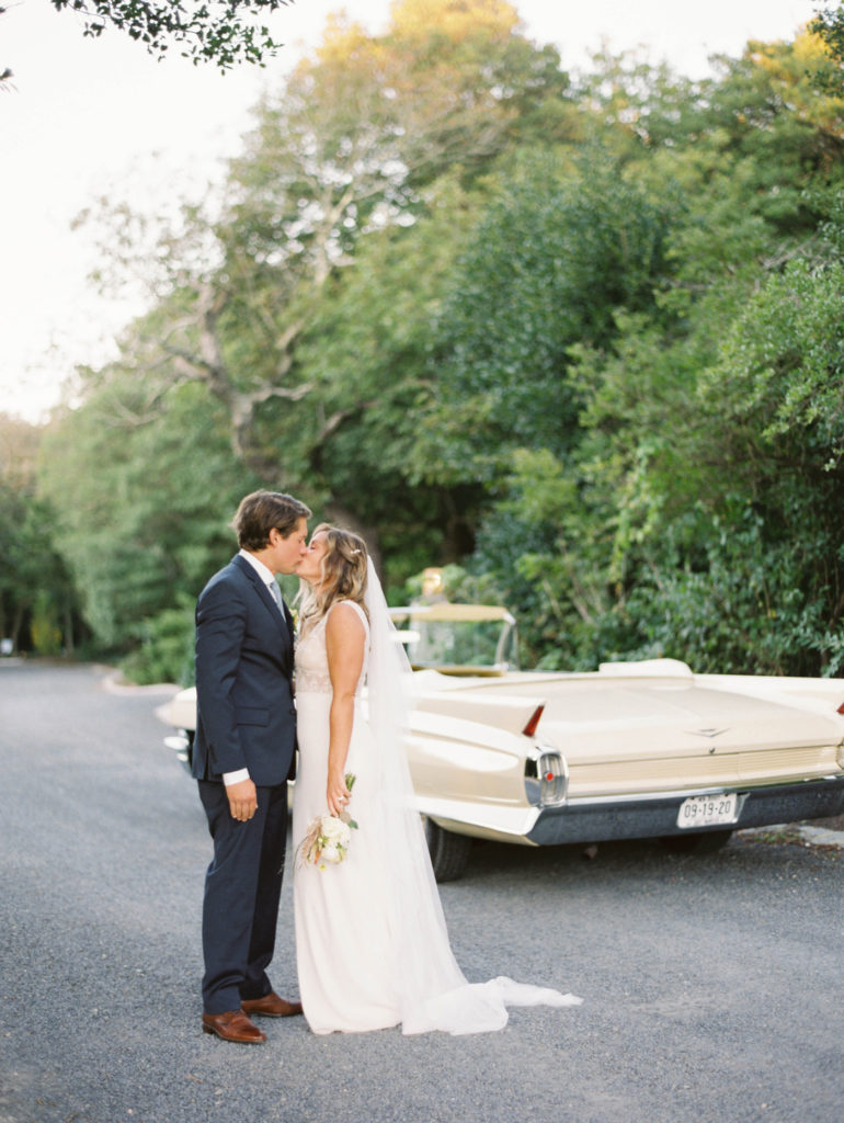 Bride and groom stand with classic Cadillac in the background while kissing | #backyardwedding photographed by Mary Dougherty