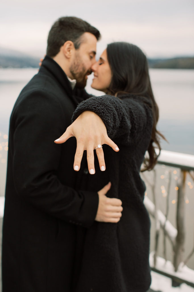 couple stands close together with hand outstretched and engagement ring on 