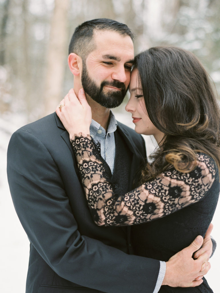 husband and wife hold each other close for portrait while looking away