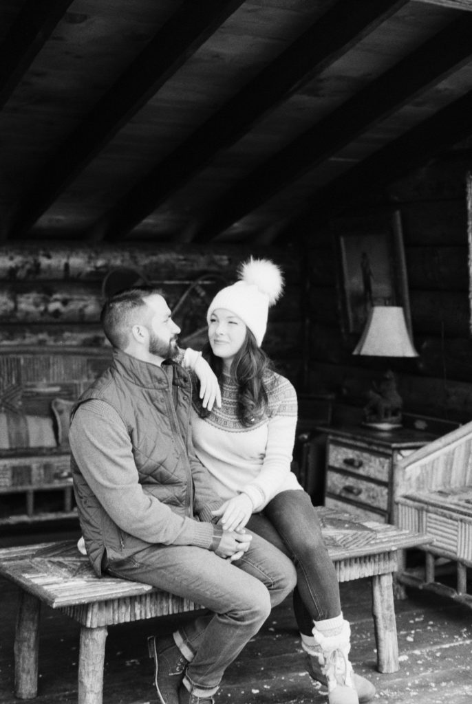whiteface lodge winter portrait session couple sits in lean to in black and white photo by Mary Dougherty