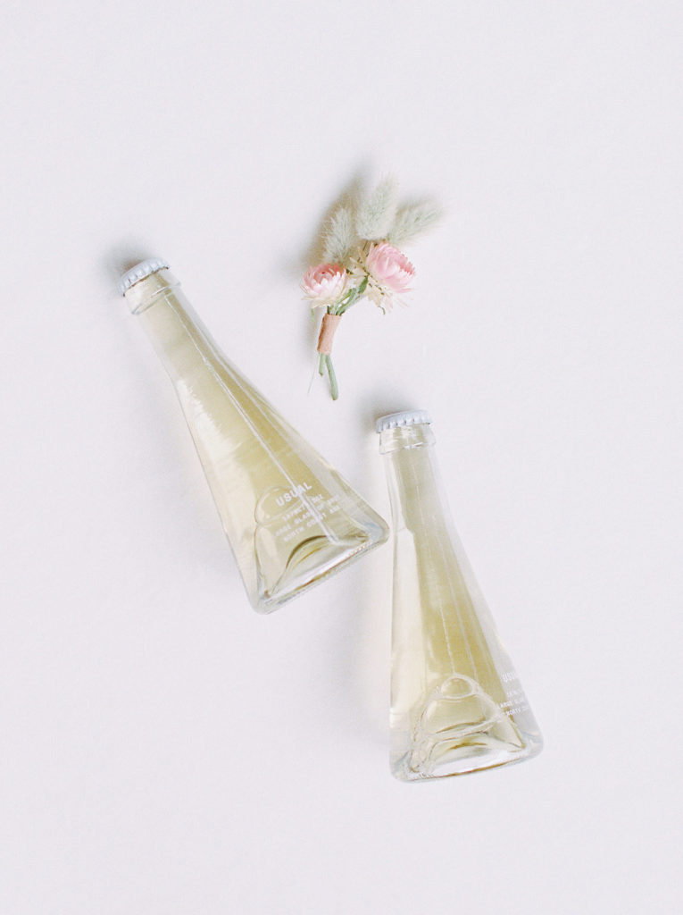 Individual champagne bottles from Usual and a boutonnière made with a bandaid for an Adirondack elopement by Mary Dougherty