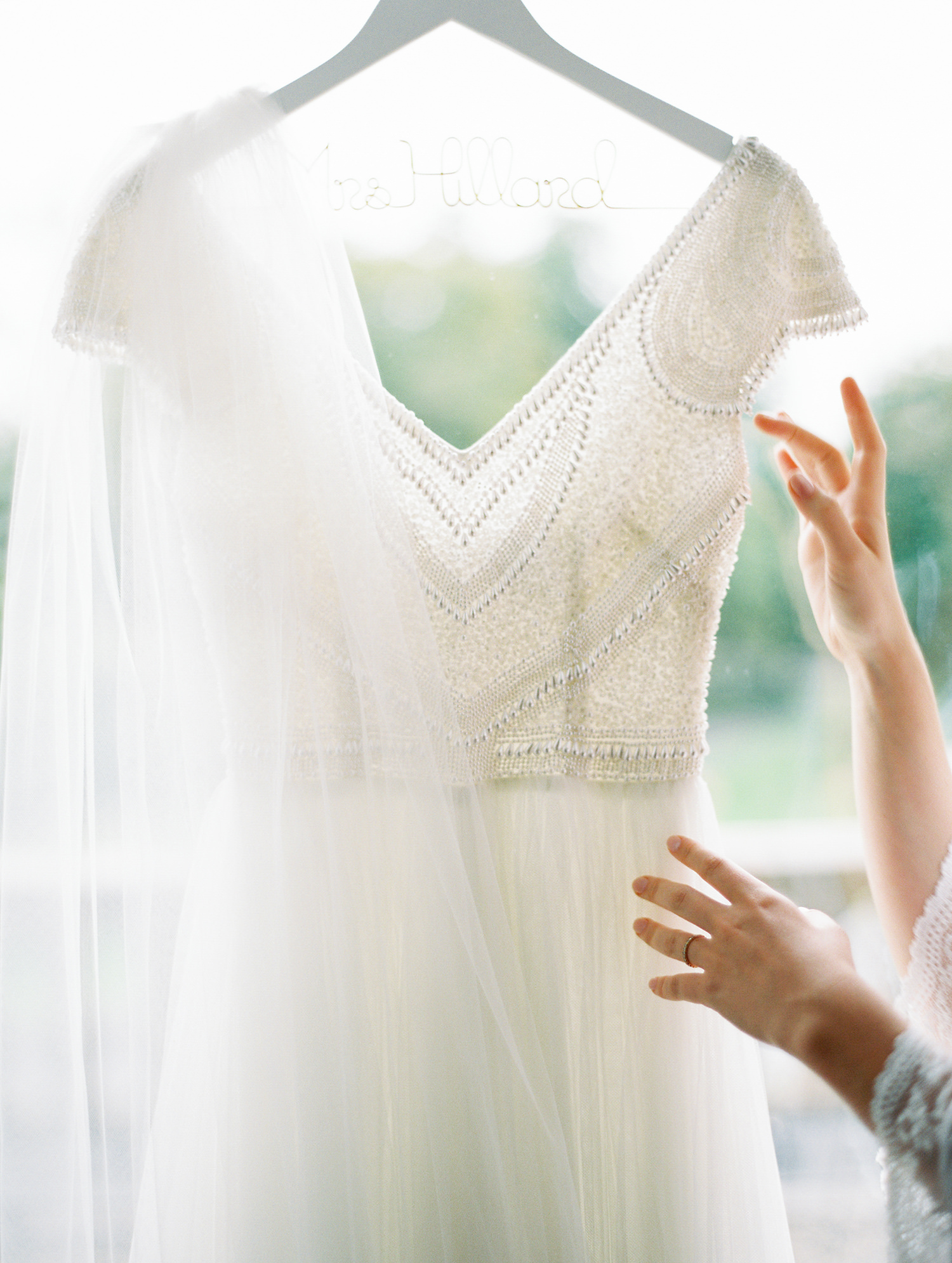 Theia beaded wedding dress delicately hanging in window