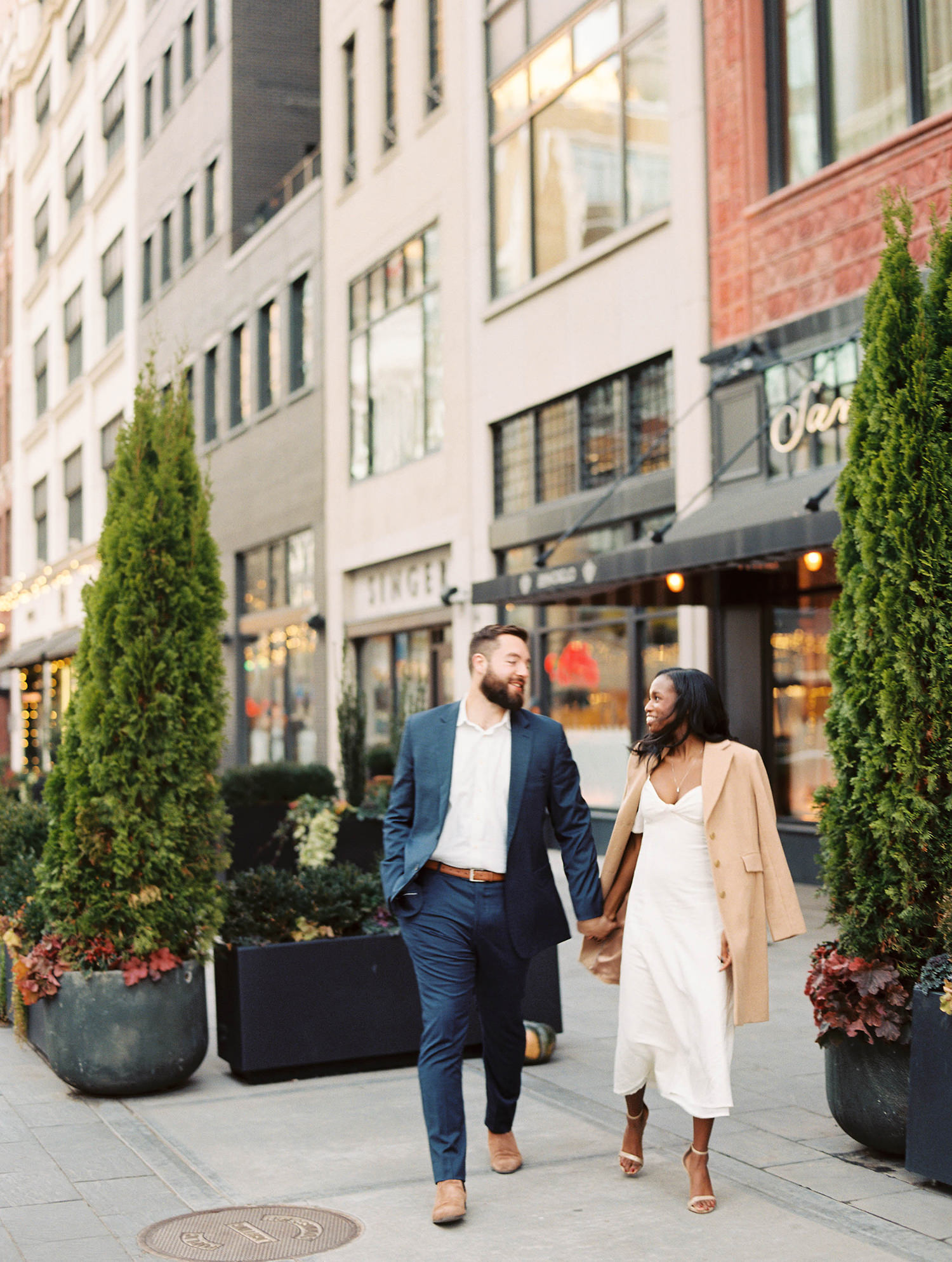 Bride and groom to be walking on street in from on Shinola Hotel Detroit