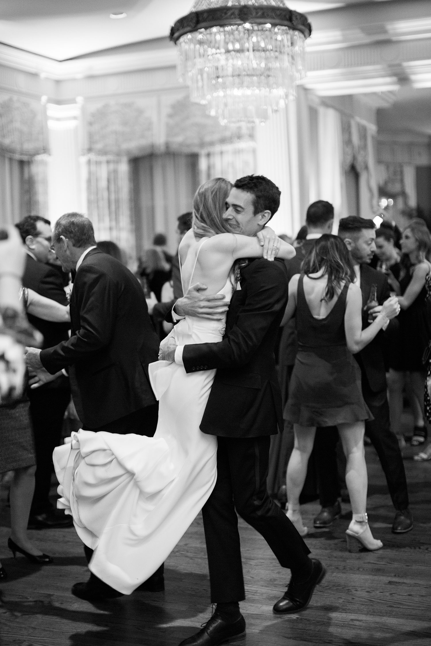 Black and white photo of bride and groom dancing after wedding