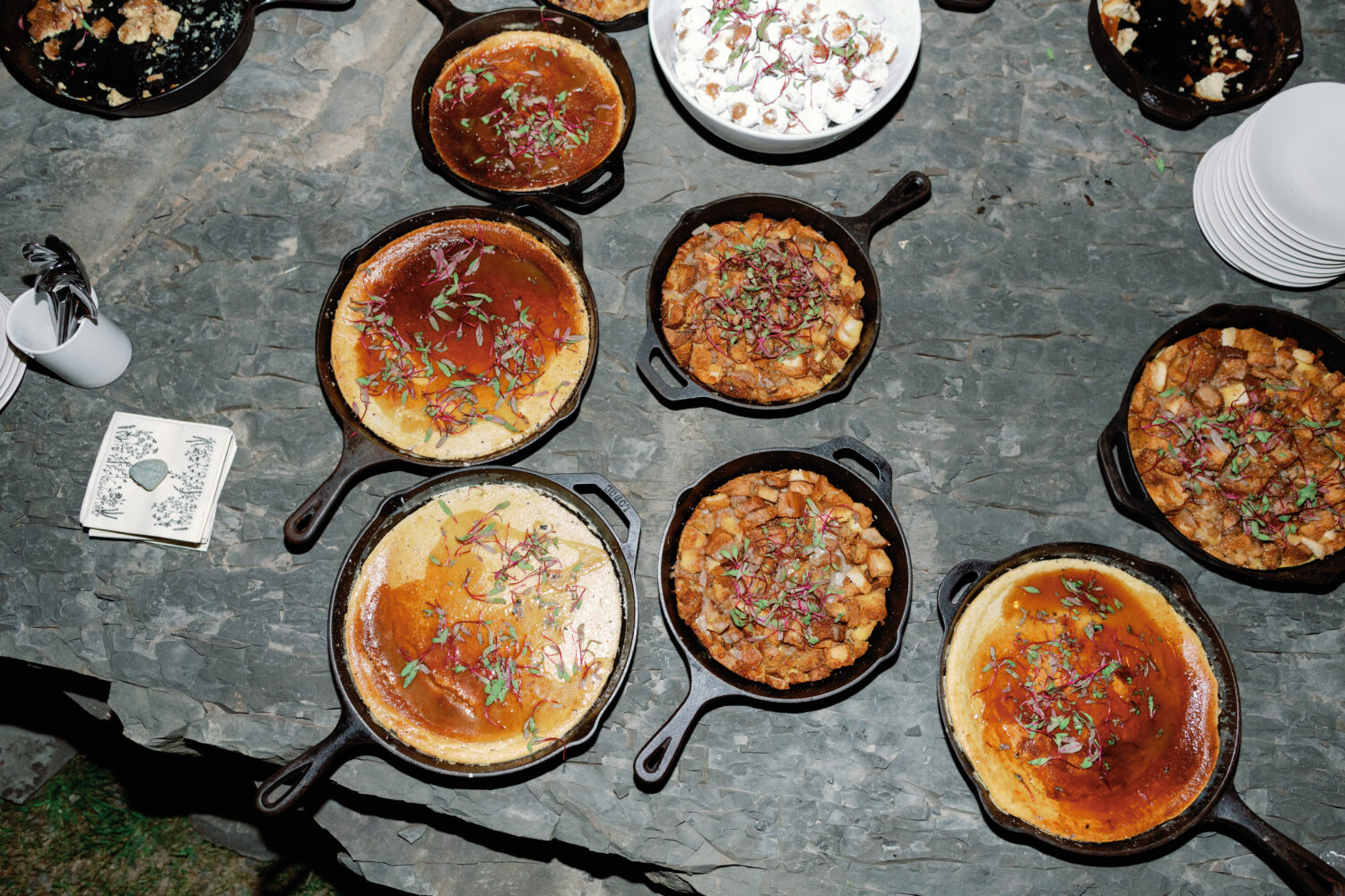 Cheesecakes sit a top a rock in cast iron pans catered by Heirloom Fire for a wedding at Gather Greene